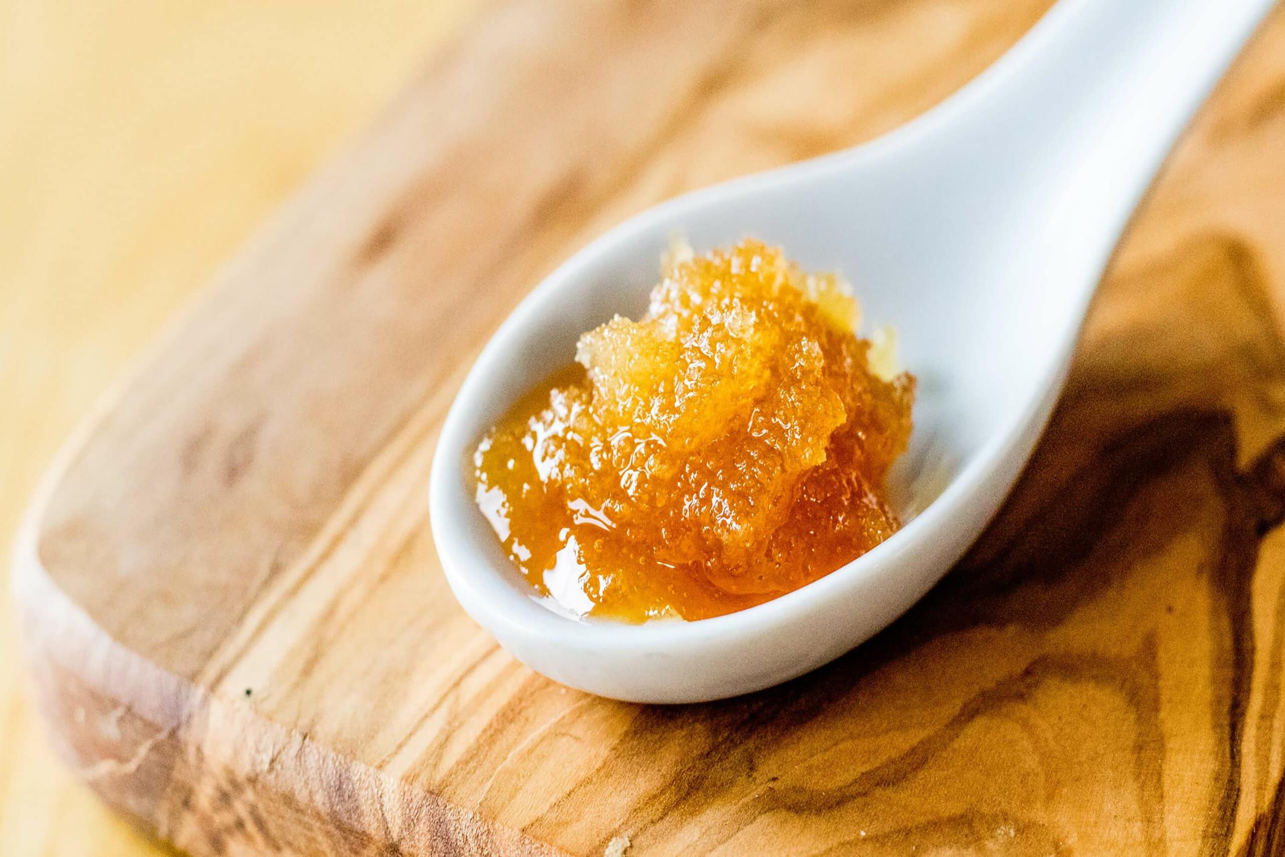 Close-up of crystallized honey on a spoon, showcasing its granulated texture and golden hue