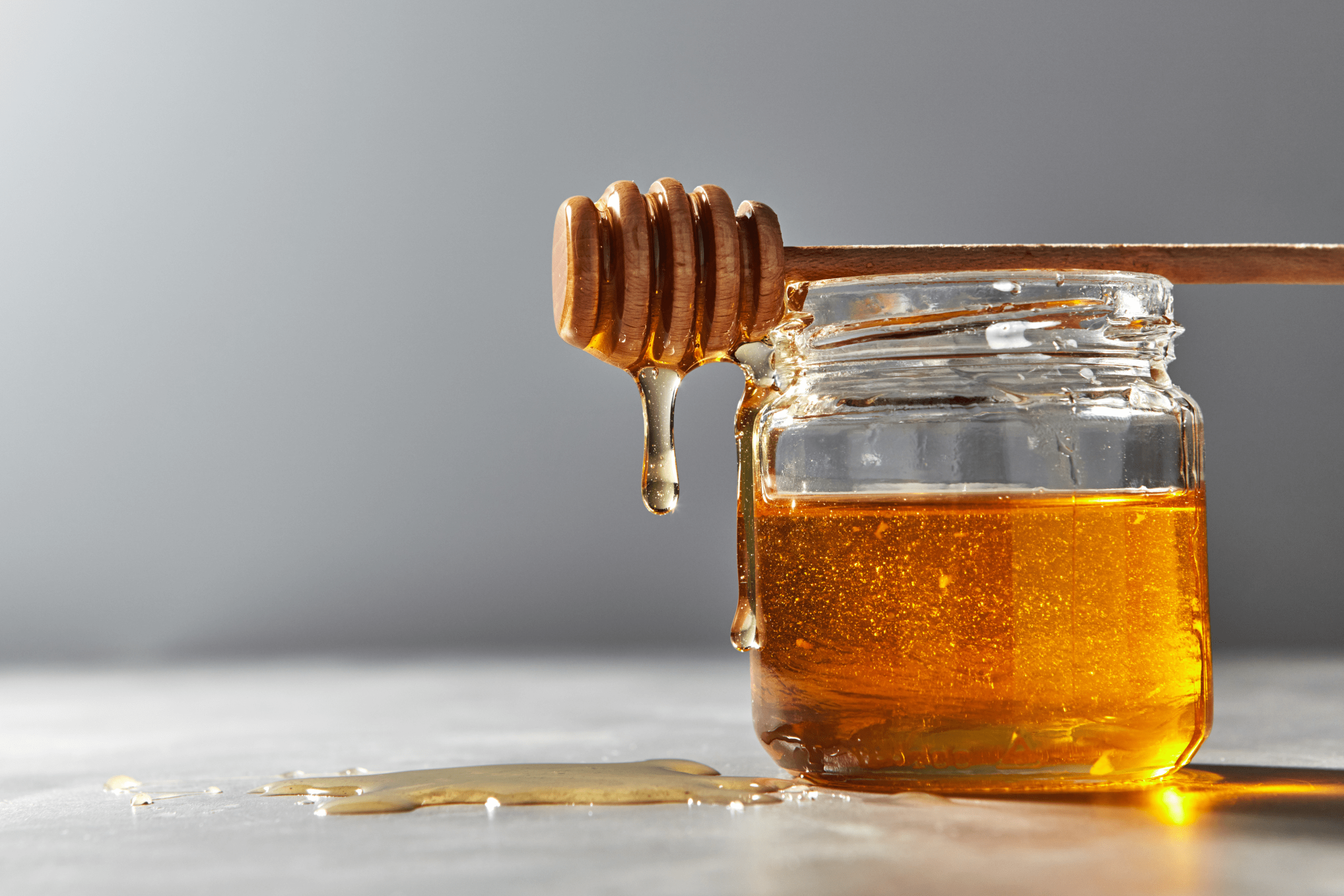 A jar of golden honey with a wooden honey dipper