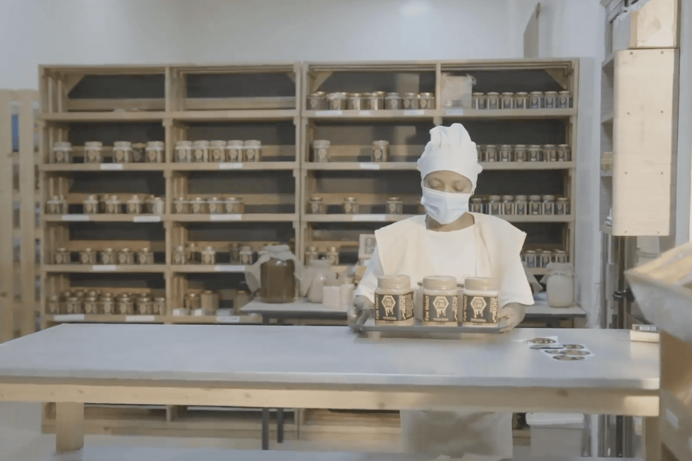 Employee placing packaged Ethiopian honey on Lal Honey facility shelves.